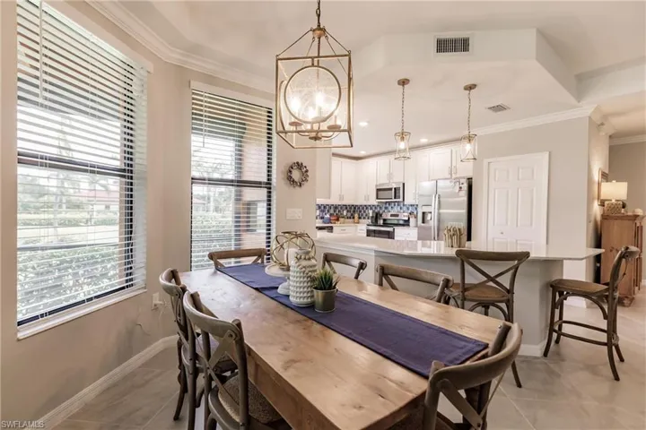 Tiled dining space featuring crown molding and a notable chandelier
