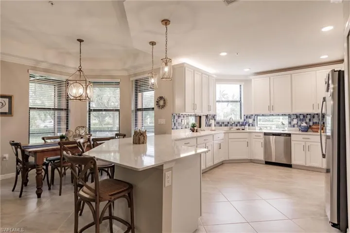 Kitchen with stainless steel appliances, a breakfast bar, light stone counters, and ornamental molding