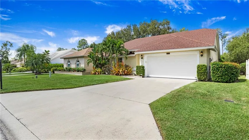 View of front facade featuring a front lawn, stucco siding, driveway, roof with shingles, and a garage