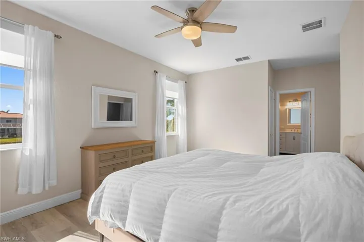 Bedroom with wood finished floors, ceiling fan, and ensuite bath