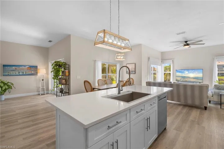 Kitchen with open floor plan, white cabinetry, pendant lighting, a ceiling fan, and light wood-type flooring