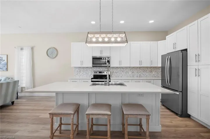 Kitchen with a center island with sink, a kitchen breakfast bar, white cabinetry, and light wood finished floors
