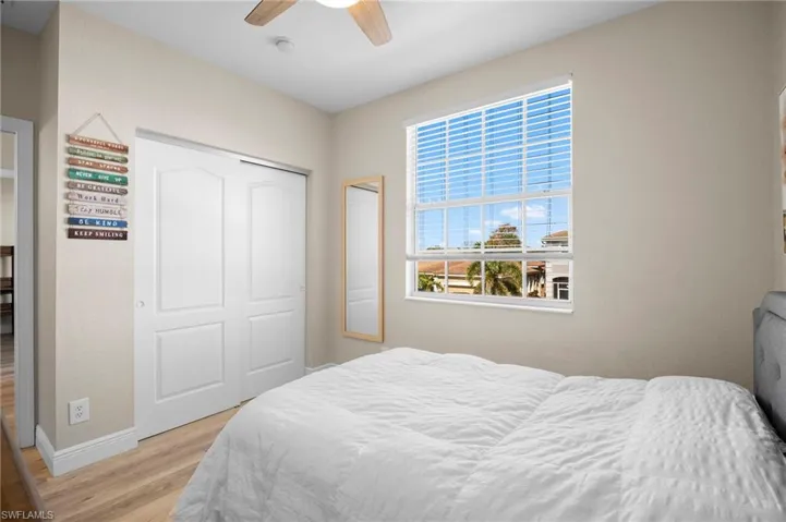 Bedroom with light wood-style flooring, ceiling fan, and a closet