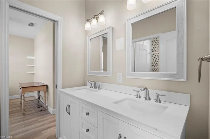 Bathroom featuring double vanity, light wood-style flooring, and a shower