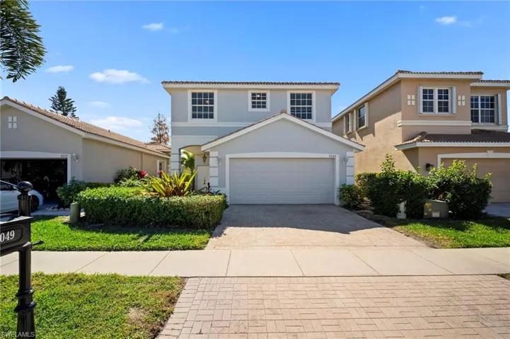 View of front facade with decorative driveway, stucco siding, and a tiled roof