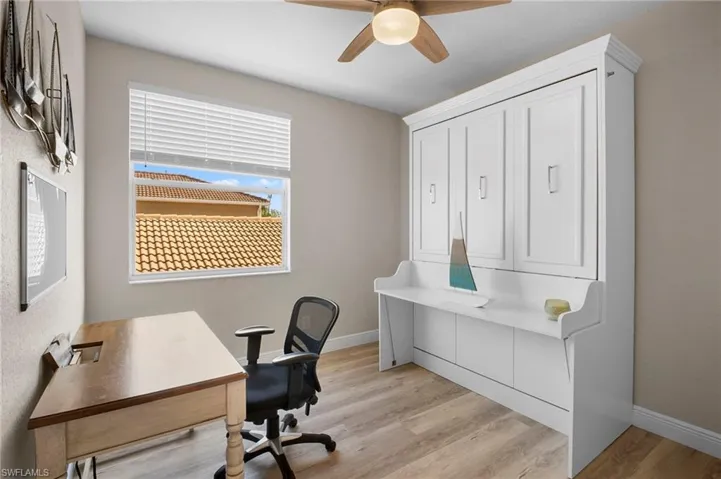 Home office with light wood-style floors and ceiling fan
