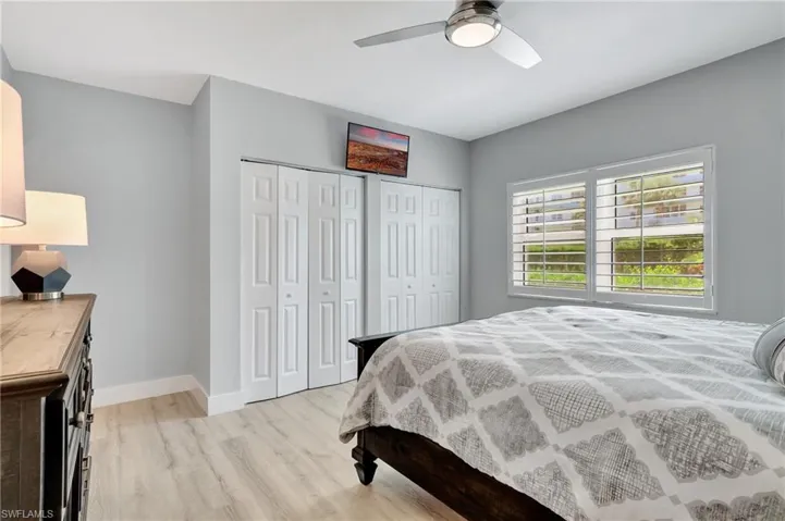 Bedroom featuring multiple closets, light hardwood / wood-style floors, and ceiling fan