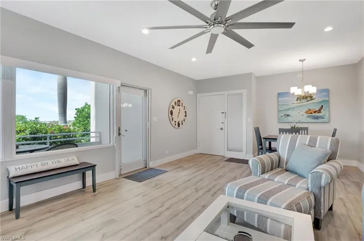 Living area featuring ceiling fan with notable chandelier and light hardwood / wood-style flooring