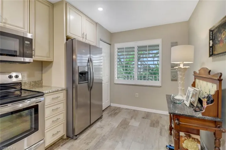 Kitchen with light hardwood / wood-style flooring, stainless steel appliances, light stone counters, and cream cabinets