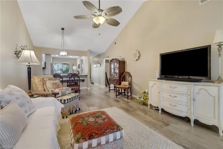 Living room featuring light hardwood / wood-style flooring, high vaulted ceiling, and ceiling fan with notable chandelier