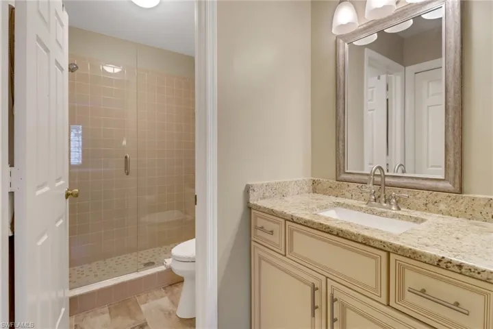 Bathroom featuring walk in shower, vanity, and toilet