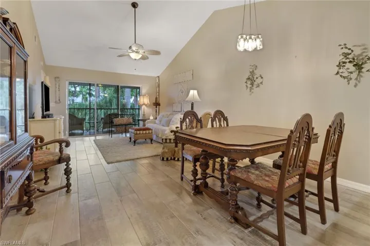 Dining room featuring light wood-type flooring, ceiling fan with notable chandelier, and high vaulted ceiling
