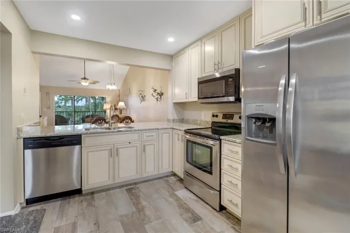 Kitchen featuring ceiling fan, appliances with stainless steel finishes, light wood-type flooring, and kitchen peninsula