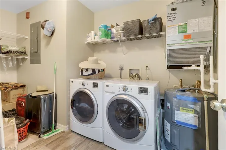 Laundry area featuring water heater, separate washer and dryer, electric panel, and light hardwood / wood-style flooring