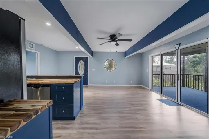 Kitchen with wood counters, blue cabinets, light hardwood / wood-style flooring, dishwasher, and ceiling fan