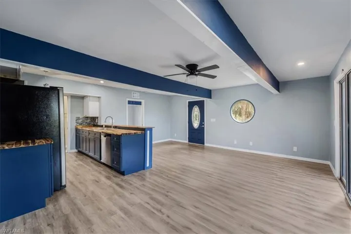 Kitchen featuring blue cabinets, beamed ceiling, ceiling fan, stainless steel appliances, and light hardwood / wood-style flooring