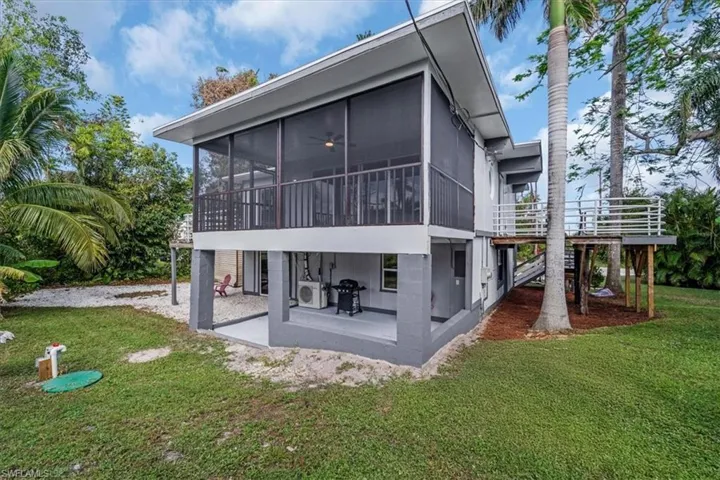 Rear view of property featuring a sunroom, a yard, and a patio area