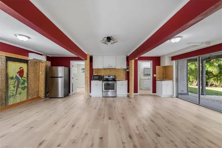 Kitchen with extractor fan, a wall mounted AC, light hardwood / wood-style flooring, appliances with stainless steel finishes, and white cabinets