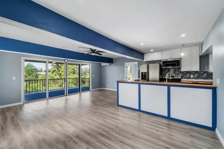 Kitchen featuring appliances with stainless steel finishes, white cabinets, light hardwood / wood-style floors, and decorative backsplash