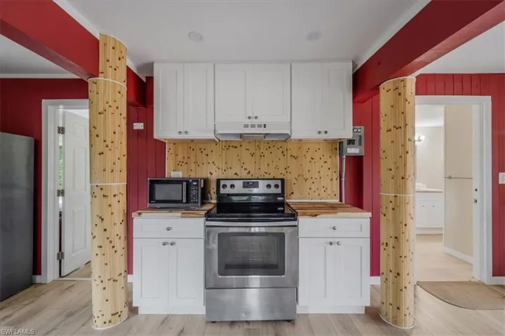 Kitchen featuring stainless steel appliances, white cabinetry, wooden counters, and light hardwood / wood-style flooring