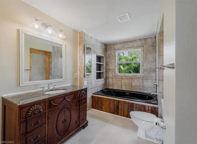 Bathroom featuring vanity, a washtub, and toilet