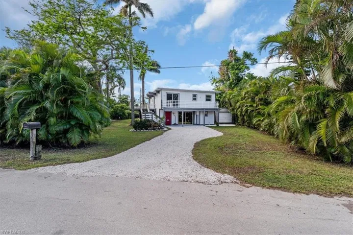 View of front of property with a garage, a front yard, and a carport