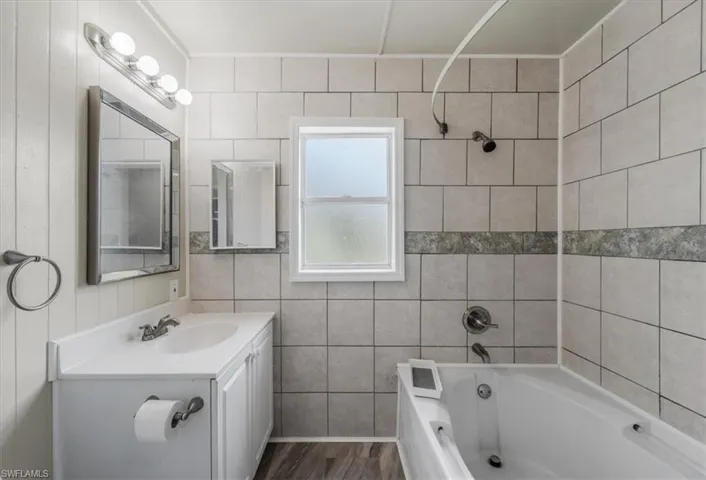 Bathroom with vanity, hardwood / wood-style flooring, and washtub / shower combination