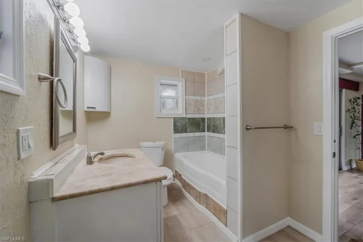 Bathroom with hardwood / wood-style flooring, vanity, toilet, and a bathtub