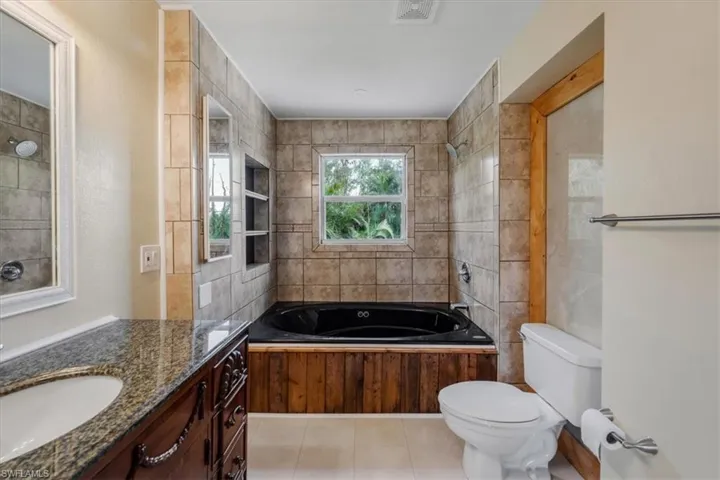 Full bathroom with vanity, tile patterned flooring, toilet, and tiled shower / bath