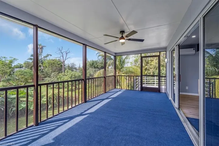 Unfurnished sunroom featuring a wall mounted air conditioner and ceiling fan