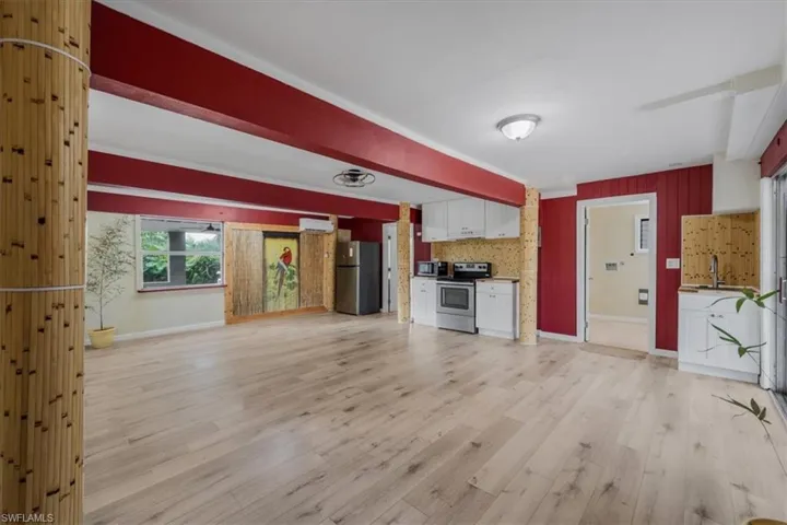 Kitchen featuring sink, white cabinetry, light wood-type flooring, a wall unit AC, and stainless steel appliances