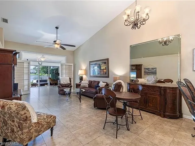 Living room featuring high vaulted ceiling, ceiling fan, light tile patterned flooring, and a chandelier