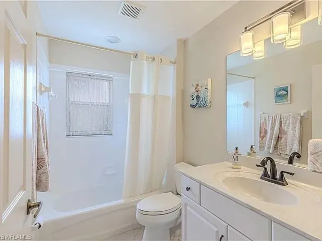 Full bathroom featuring shower / bathtub combination with curtain, vanity, and light tile patterned flooring