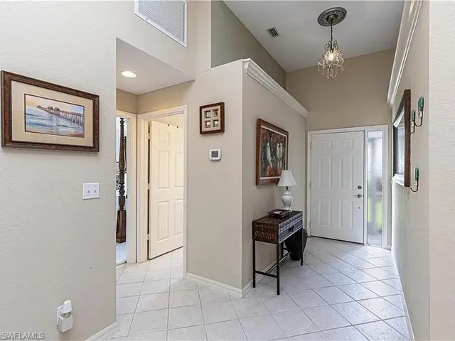 Foyer with light tile patterned floors, a textured wall, and a chandelier