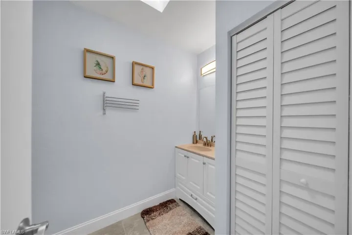 Bathroom featuring a single vanity with a light-colored countertop, white cabinetry, and a mirrored wall