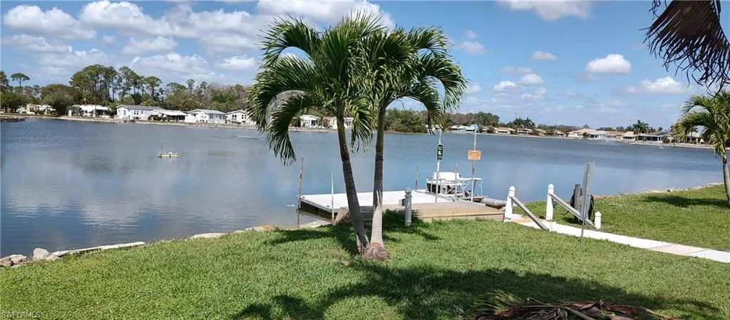 Dock featuring a water view, a lawn, and a residential view