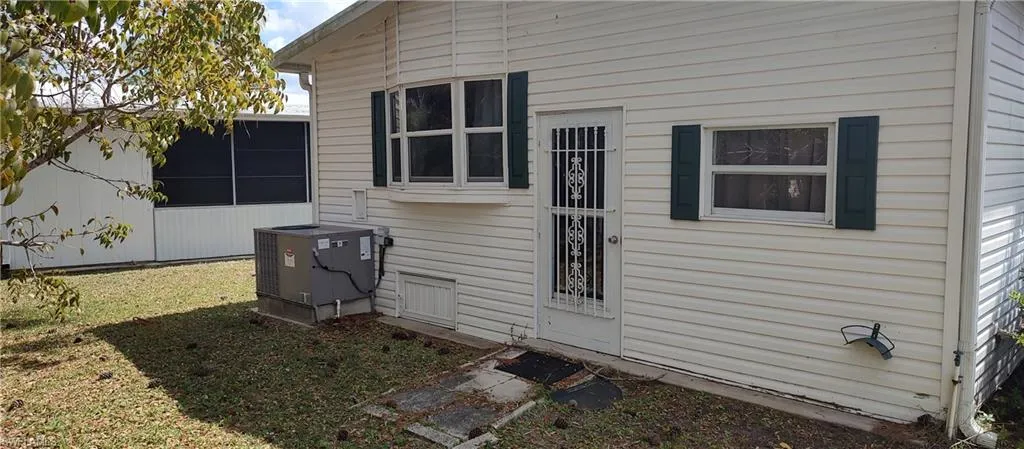 View of side of property with a central AC unit and a lawn