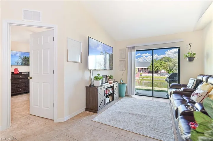 Living room with light tile patterned flooring and lofted ceiling