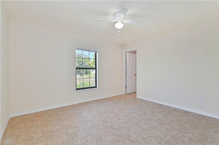 Empty room featuring light tile patterned floors and a ceiling fan
