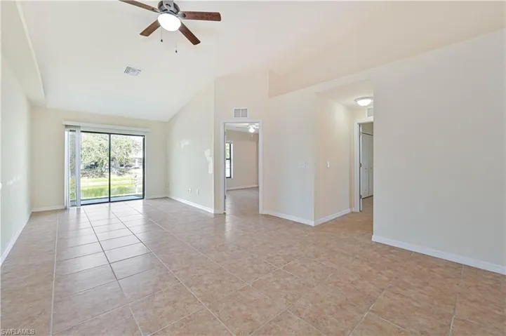 Empty room featuring ceiling fan, lofted ceiling, and light tile patterned floors