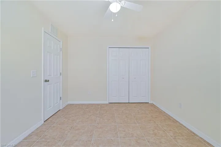Unfurnished bedroom featuring a closet, a ceiling fan, and light tile patterned floors