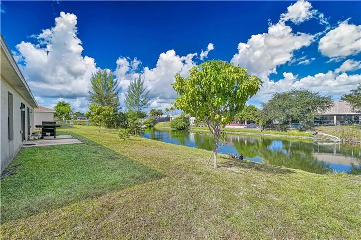 View of grassy yard featuring a water view and a patio area