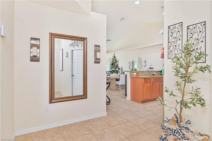 Hallway featuring lofted ceiling, light tile patterned floors, and recessed lighting