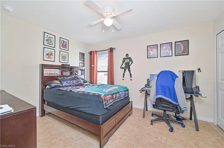 Bedroom featuring light tile patterned floors, a ceiling fan, and an office area