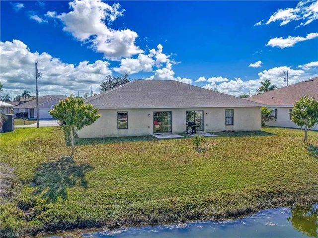 Rear view of house with a lawn, a water view, and stucco siding