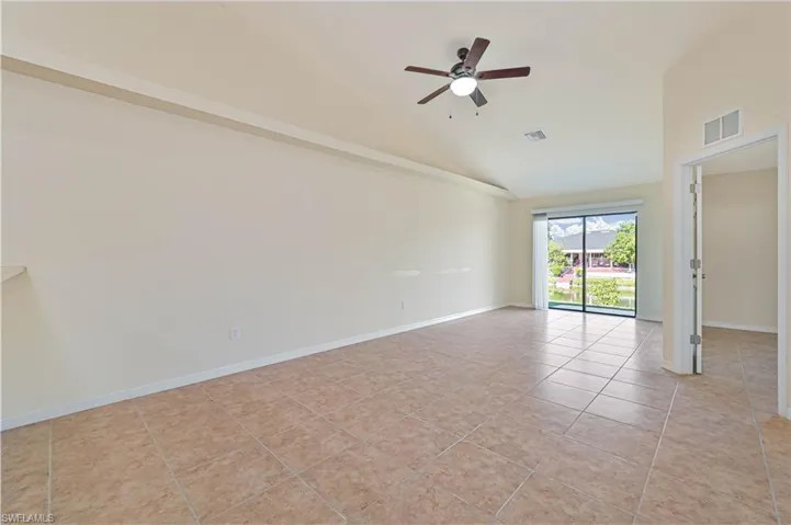 Empty room with ceiling fan, high vaulted ceiling, and light tile patterned floors