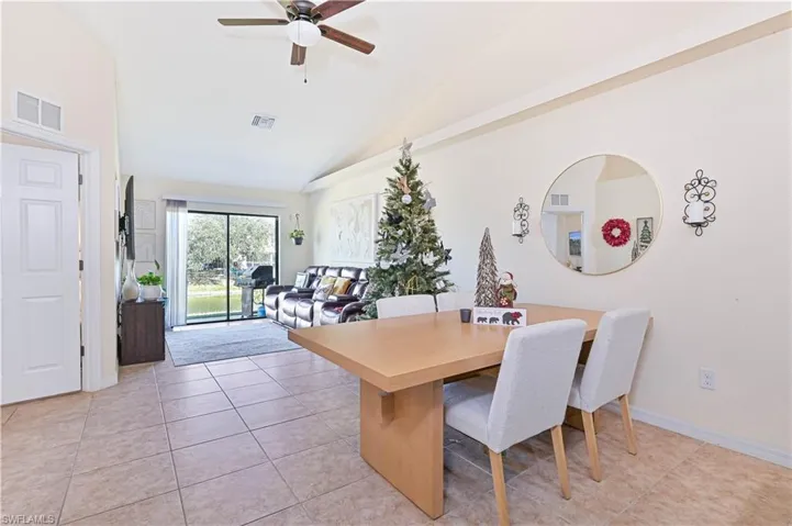 Dining space featuring light tile patterned floors, a ceiling fan, and high vaulted ceiling