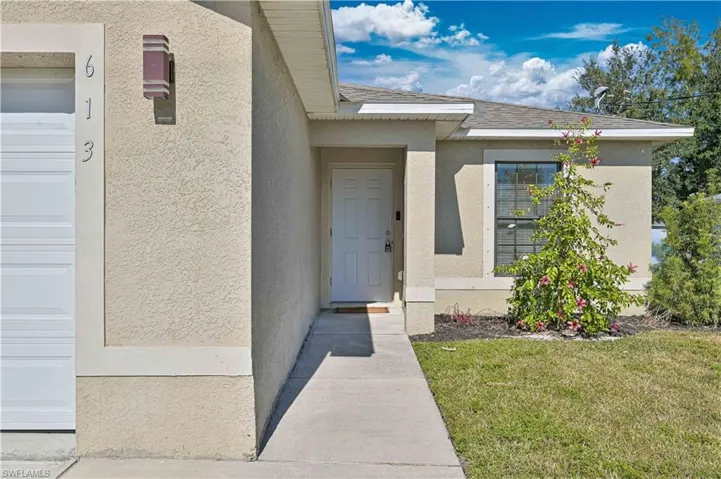 Entrance to property featuring stucco siding and a lawn