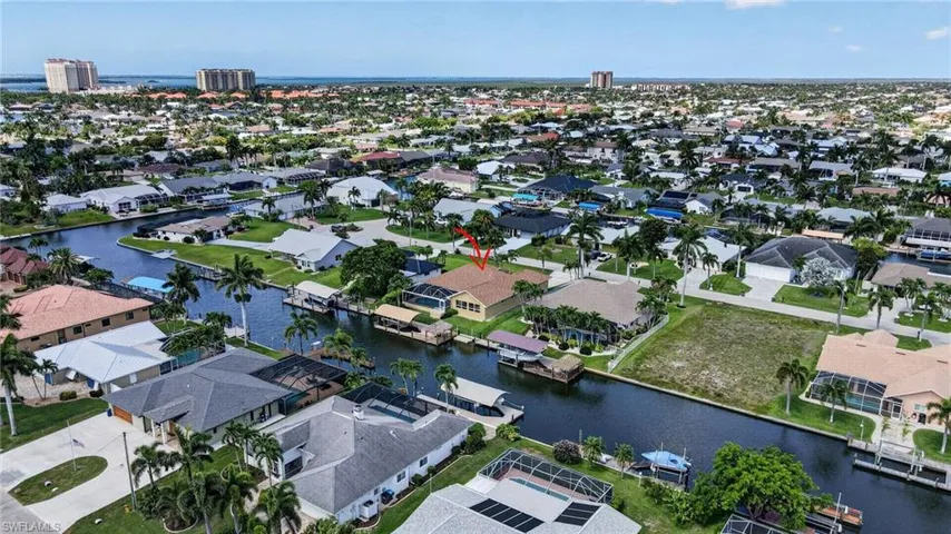 Waterfront property featuring a private boat dock, mature palm trees, an extended screened lanai, and a concrete tile roof