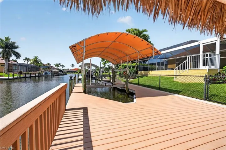 Waterfront property featuring a composite deck and railing, boat lift with canopy, and direct canal access
